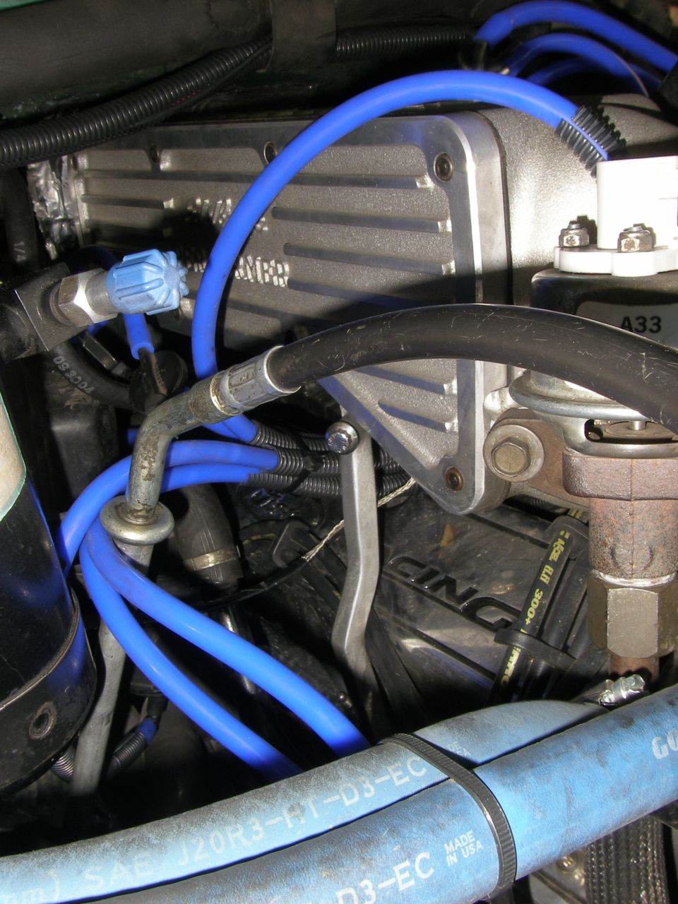 Engine bay with finned aluminum valve cover and bright blue plug wires and vacuum lines