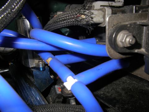 1990 Ford Bronco - Tight close-up of bright blue silicone vacuum lines routed across an engine bay, several crossing over each other with a white plastic tee…