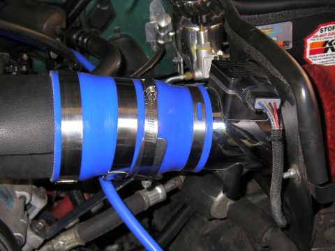 1990 Ford Bronco - Close-up of a polished aluminum intake tube joined by blue silicone couplers and stainless worm-drive clamps in an engine bay, feeding towa…