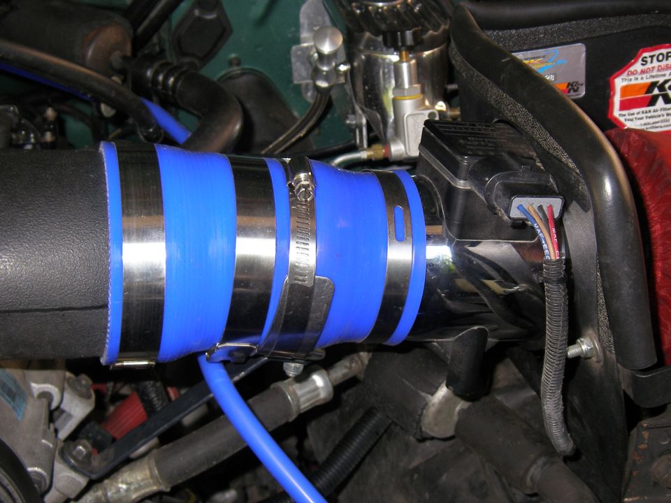 Polished intake tube with blue silicone couplers and clamps feeding a MAF sensor and K&N filter