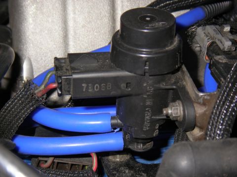 1990 Ford Bronco - Close-up of a vacuum control solenoid with blue hoses and wiring, showing 'MADE IN CANADA' text.