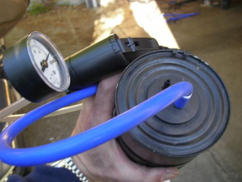 1990 Ford Bronco - A gauge and pump are connected to a component, likely for testing vacuum pressure.