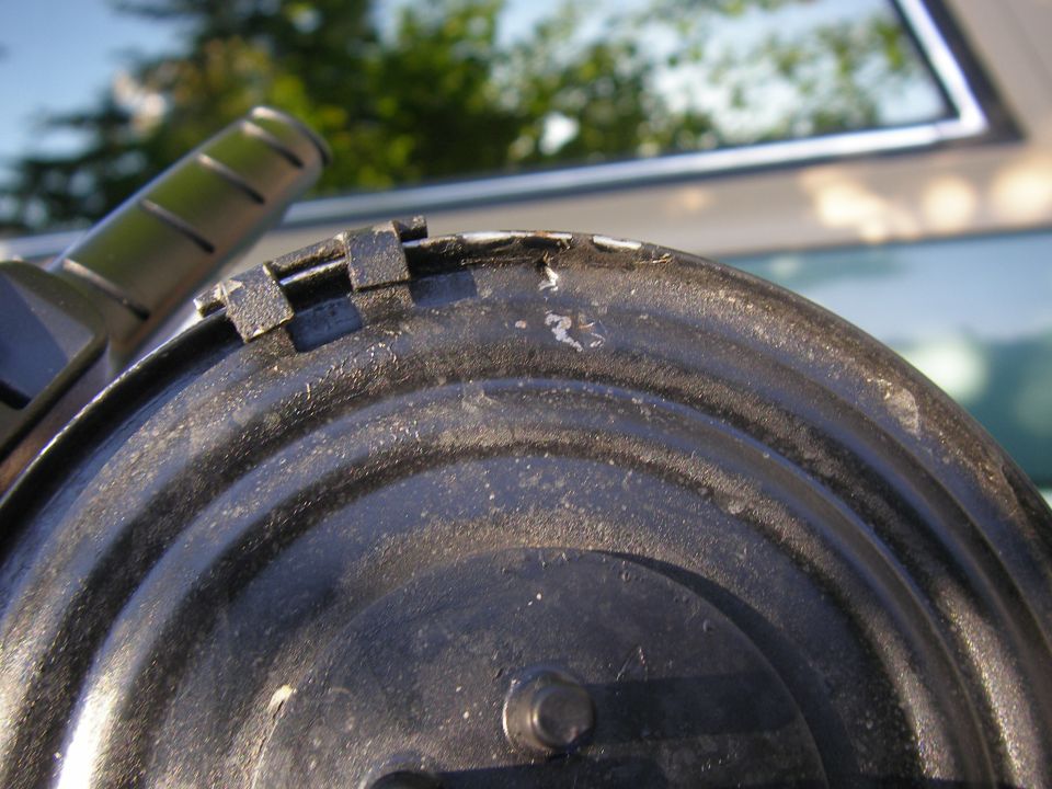 Black vacuum hose connected to a metal drum with visible wear and tear