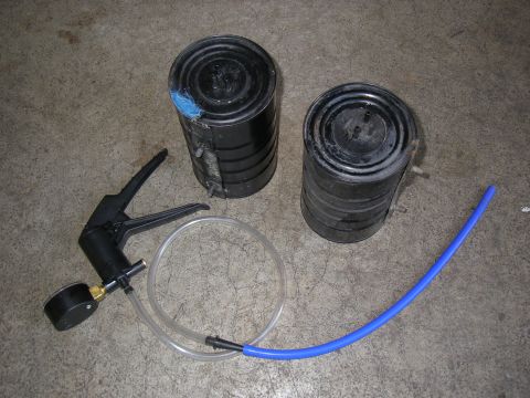 1990 Ford Bronco - Vacuum pump and canisters are laid out on a concrete floor.