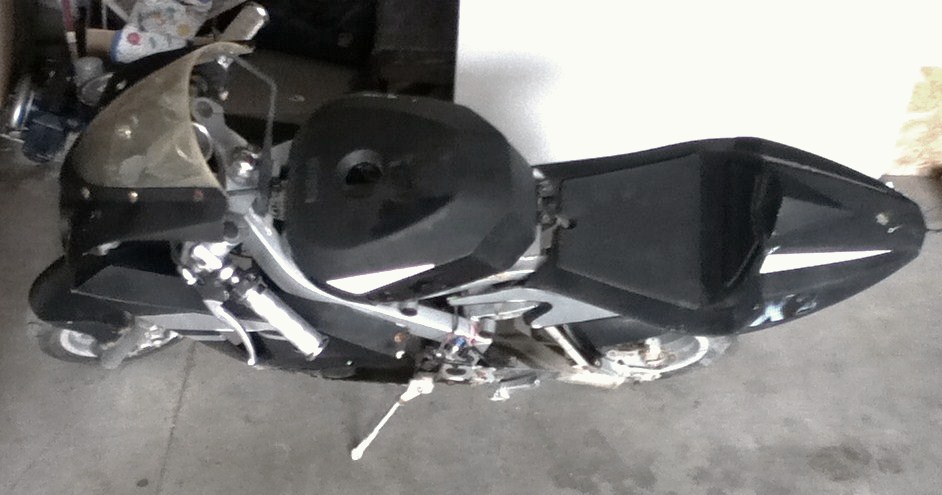 Black sport motorcycle with a clear windshield and silver frame, viewed from the side