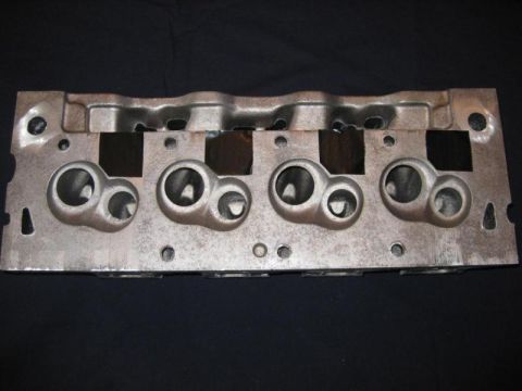1972 Ford Ranchero - A metal engine cylinder head is shown against a dark background, with visible intake ports.