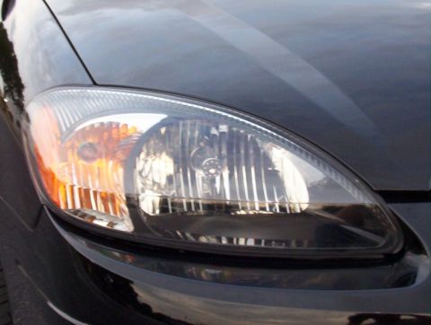 2003 Ford Taurus - Close-up view of a black car's headlight assembly, showing the clear lens and orange turn signal.