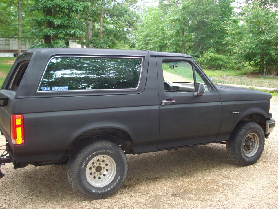 Black 1993 Ford Bronco parked on gravel, side view