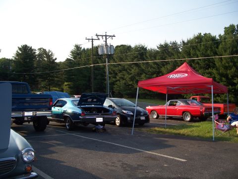 1971 Ford Ranchero - A red coupe, possibly a 1970 model, is parked under a tent at an outdoor event.
