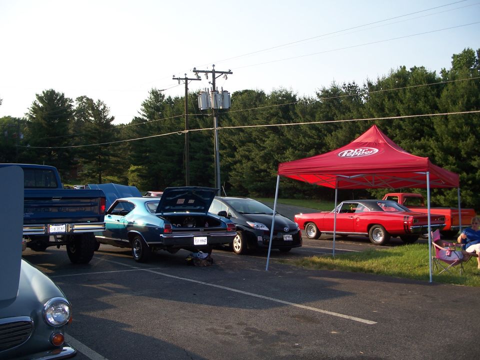 Red coupe with black roof and chrome wheels parked under a red tent