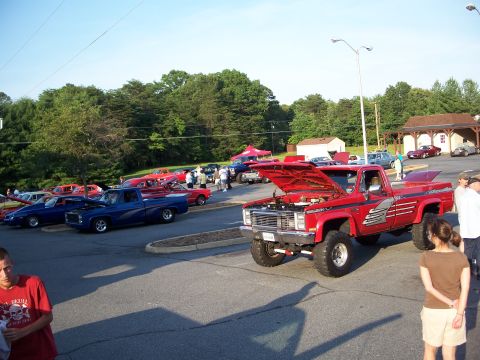 1971 Ford Ranchero - A red pickup truck is displayed with its hood up at a car show, surrounded by other vehicles.