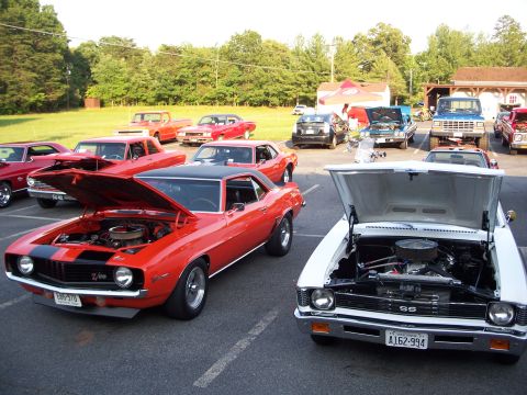 1971 Ford Ranchero - A collection of vintage vehicles, including muscle cars and pickup trucks, are displayed outdoors with their engines visible.