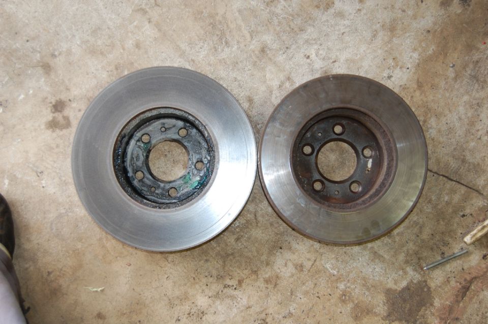 Two used brake rotors on a concrete surface
