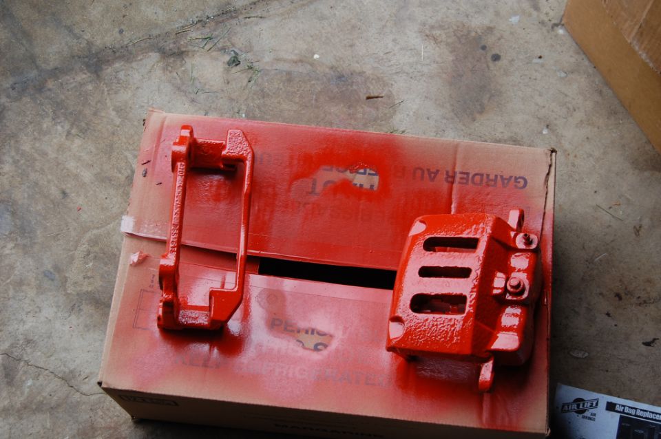 Two red brake calipers on a cardboard box