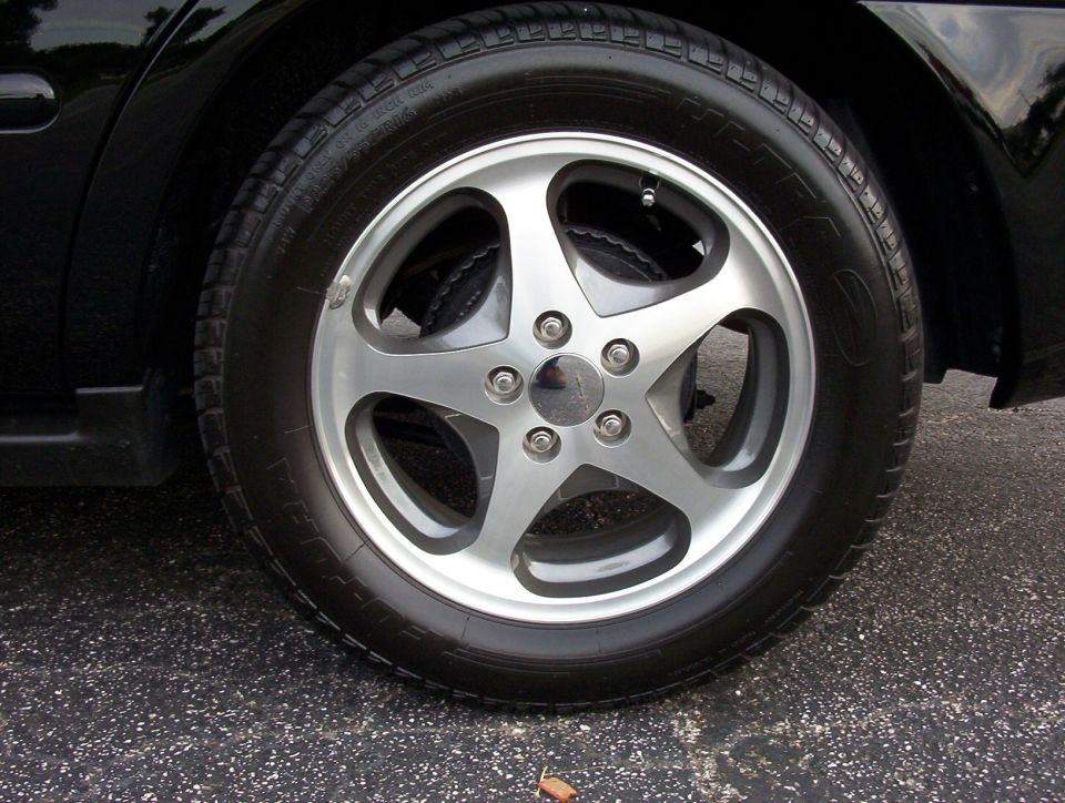 Close-up of a silver five-spoke alloy wheel and low-profile tire on a black car