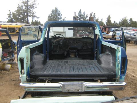 1978 Ford Bronco - Rear view of a blue 1978 Ford Bronco in a junkyard, with its doors and roof removed.