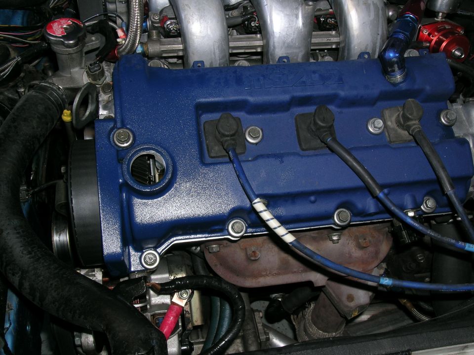 Blue painted engine valve cover with spark plug wires and intake manifold