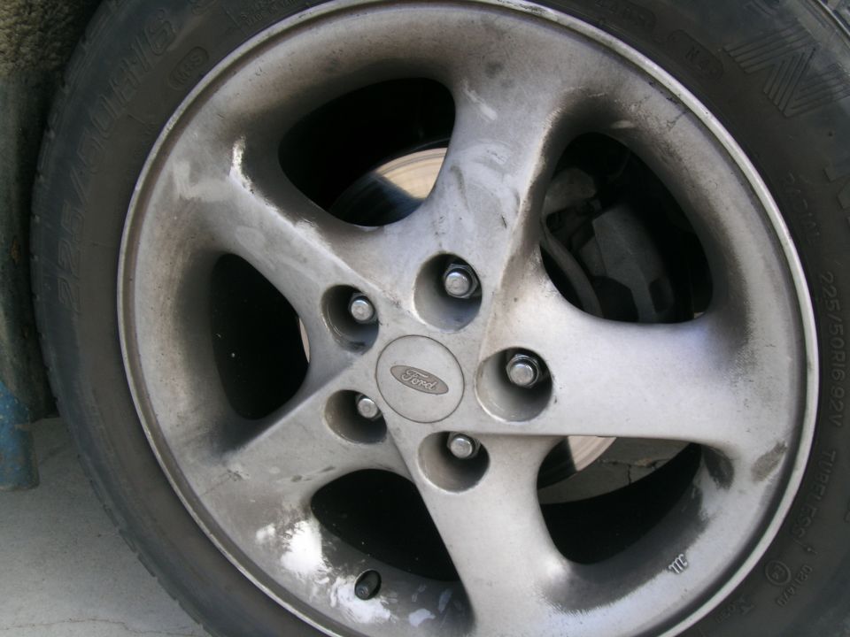 Close-up of a silver 5-spoke Ford wheel with a Ford logo center cap