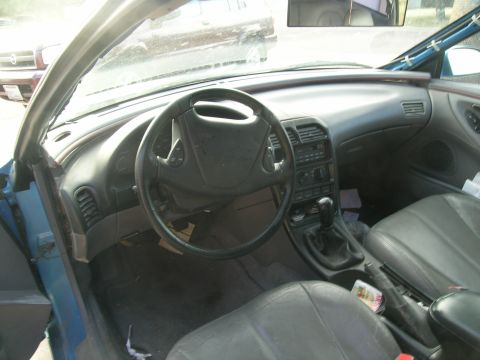 1995 Ford Probe - The interior of a car is shown, with a manual transmission and dashboard details visible. Another vehicle is seen outside.
