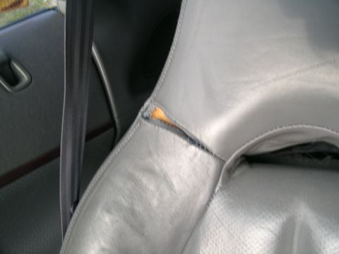 1995 Ford Probe - The interior of a vehicle shows a torn seat cushion and a seatbelt.