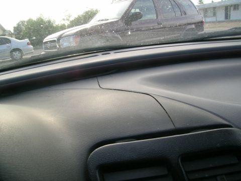 1995 Ford Probe - View from inside a vehicle, showing the dashboard and a reflection of a dark SUV in the windshield.