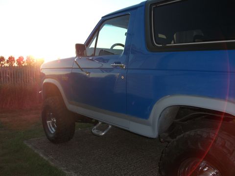 1982 Ford Bronco - This blue SUV, likely from the early 1980s, is viewed from the side as the sun sets.