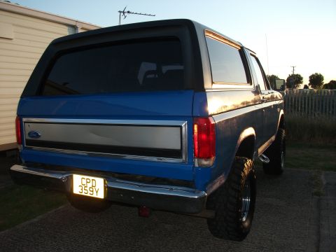1982 Ford Bronco - The rear of a blue Ford Bronco is shown in this photo, with a chrome bumper and tinted windows.