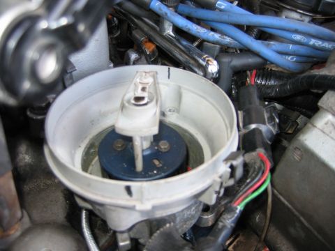 1992 Ford Bronco - Close-up of a Ford distributor cap and rotor assembly with blue spark plug wires visible.