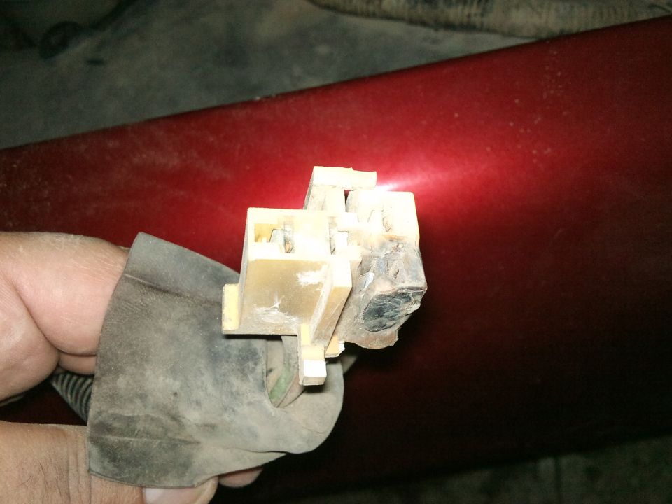 Blower motor resistor connector with damaged pins against red car body