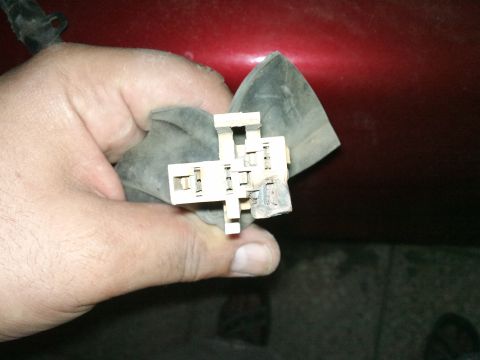 1998 Ford Crown Victoria - A close-up shows a hand holding a dirty electrical connector with a gray rubber boot.
