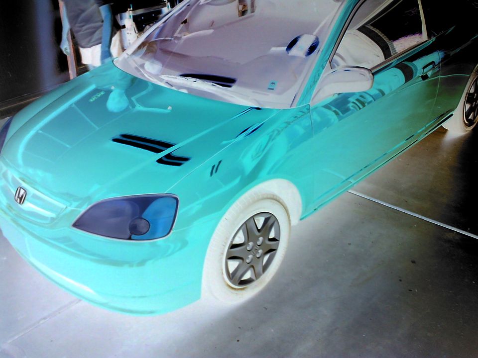 Teal car, front quarter view, with aftermarket wheels and hood vents