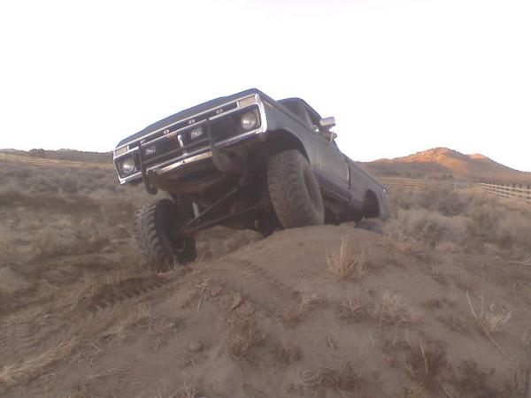 Dark Ford F-series 4x4 pickup climbing a dirt hill at dusk