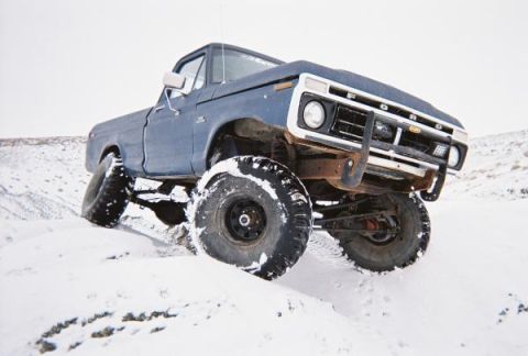1976 Ford F-100 - This lifted 1976 Ford F-100 navigates a snowy terrain with its large off-road tires.