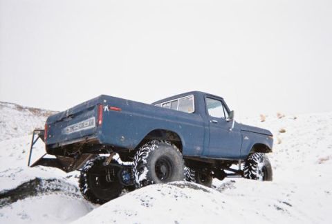 1976 Ford F-100 - 1976 Ford F-100 pickup truck navigates a snowy terrain with its large off-road tires.
