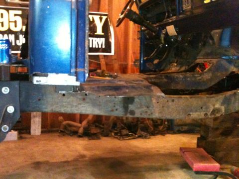 1976 Ford F-100 - Close-up view of a blue truck's cab and chassis frame, showing structural components in a workshop setting.