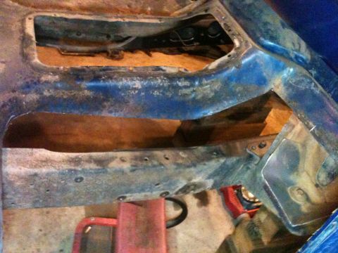 1976 Ford F-100 - Close-up of a heavily rusted vehicle frame section, showing cutouts and structural elements.