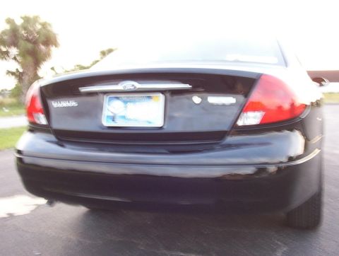 2003 Ford Taurus - The rear of a black sedan is shown, with a license plate and taillights visible.