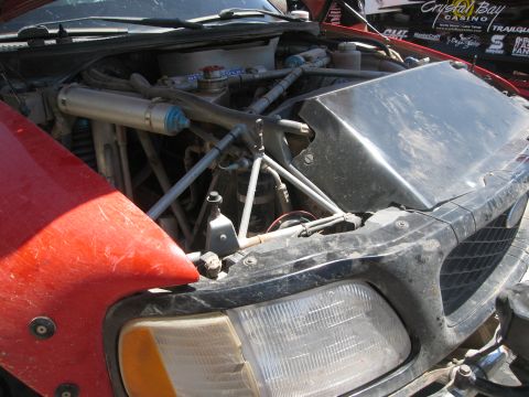 1986 Ford Bronco - The engine bay of a modified vehicle, various aftermarket parts and racing decals visible in the background.