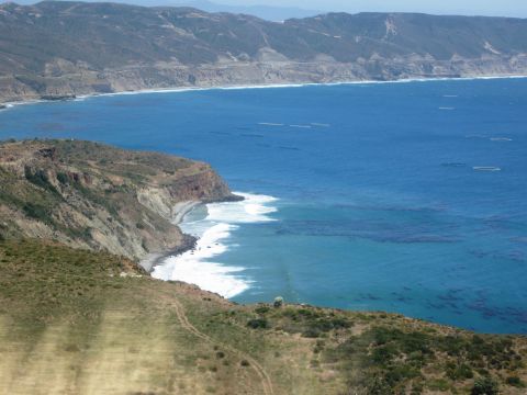 1986 Ford Bronco - A scenic view of the California coast, cliffs meeting the blue ocean with white-capped waves.