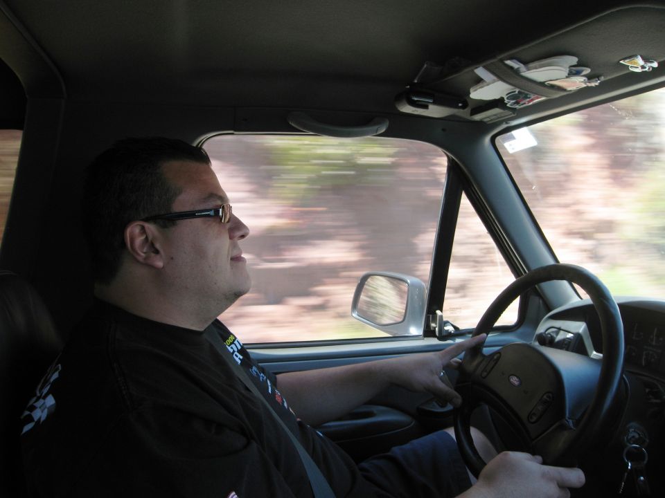 Man wearing glasses drives a truck, looking out the passenger window