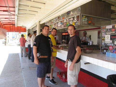 1986 Ford Bronco - A food counter is staffed by a vendor while three men stand in front of it.