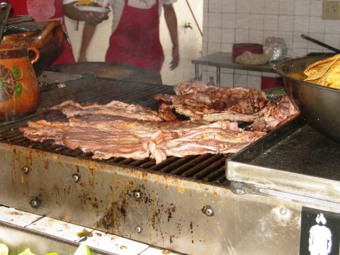 1986 Ford Bronco - Meat is grilled in an outdoor food stall, with people in aprons visible in the background.