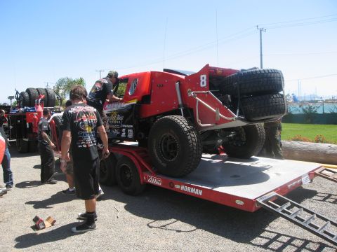 1986 Ford Bronco - A custom off-road truck is being loaded onto a trailer, with several people assisting.