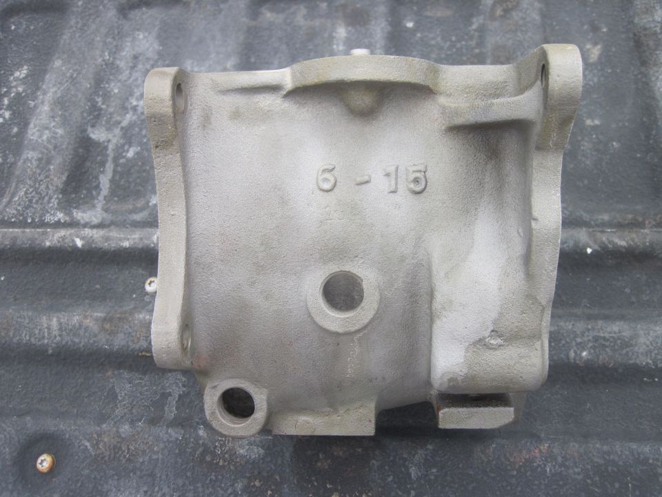 Metal casting with '6-15' stamped on it, resting on a dark surface
