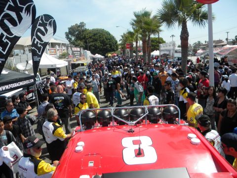 1986 Ford Bronco - A crowd gathers around a red vehicle with a large number 8 on its roof.