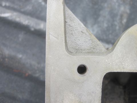 1979 Ford Bronco - Close-up of a metal casting, possibly an engine part, with a visible hole and a stamped number.