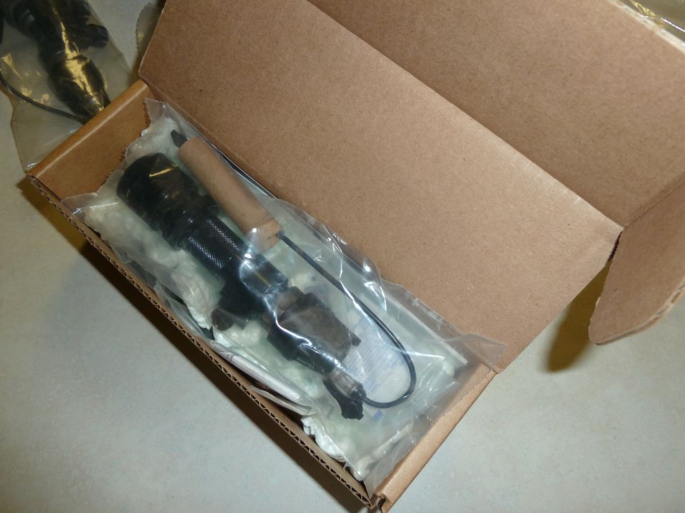 Automotive part, possibly a fuel pump or similar component, in plastic packaging inside a cardboard box