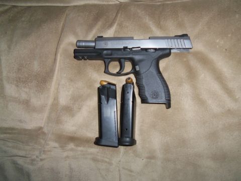 2000 Mercury Grand Marquis - A pistol and two magazines are displayed on a brown, textured background. The word 'TAURUS' is visible on the slide.