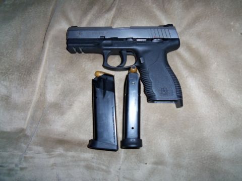 2000 Mercury Grand Marquis - A pistol and two magazines are displayed on a textured surface.