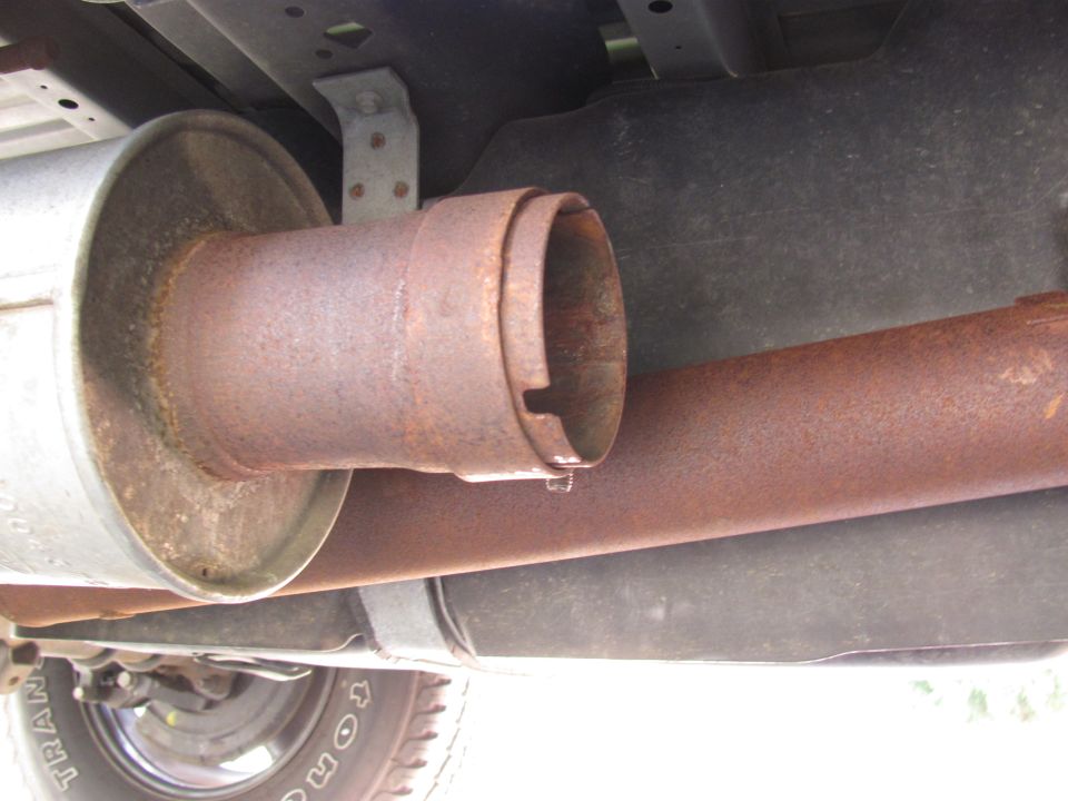 Underside view of a rusty exhaust pipe and muffler on a truck